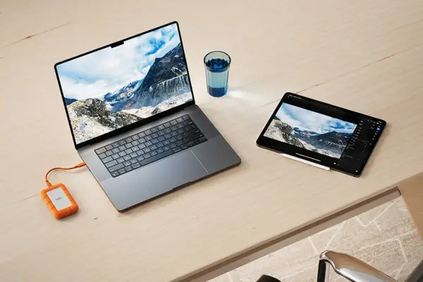Ein Laptop und ein Tablet mit Berglandschaft, verbunden mit einer externen Festplatte. Ideal für den Datenaustausch zwischen exFAT Windows und Mac.